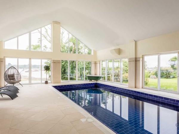 The indoor saltwater pool in the Spa Lodge at Screebe House, framed by large windows onto the garden