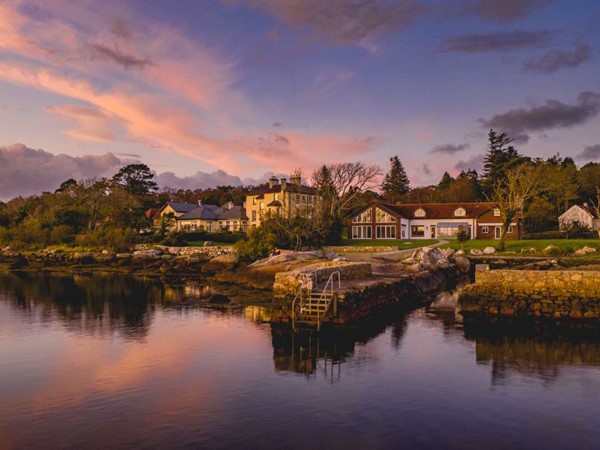 Screebe House at dusk on the shores of Camus Bay, Connemara, its lights reflected in still water