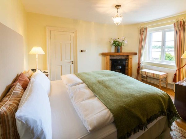 A country-house bedroom at Screebe House with a green throw and a view over the water